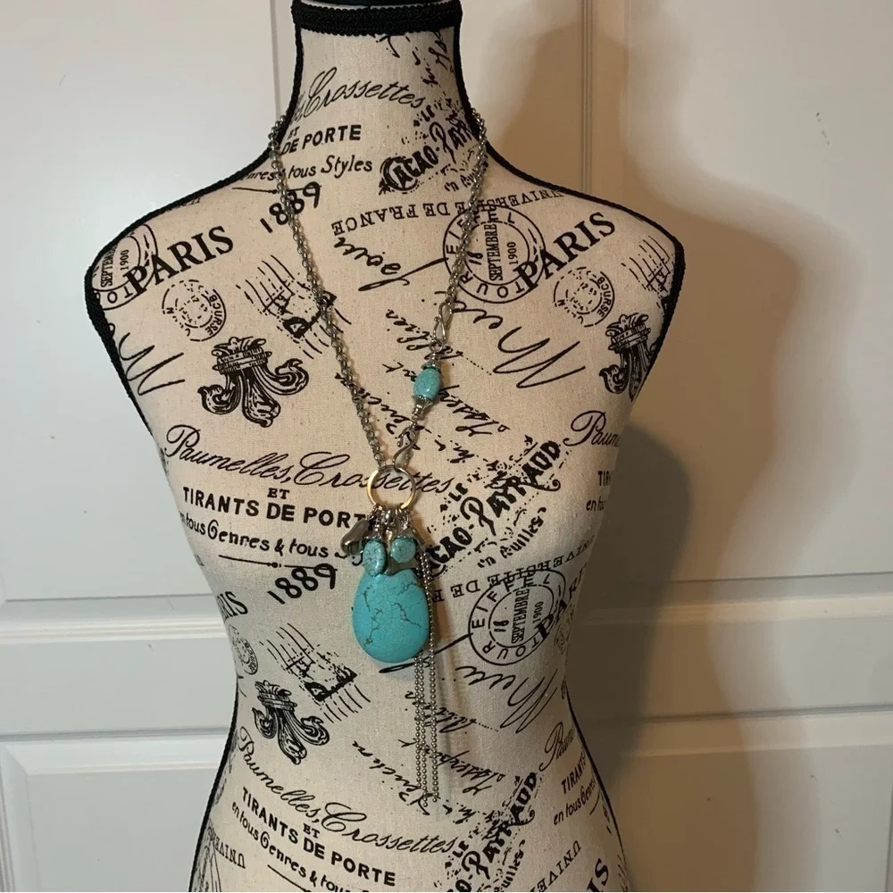 Silver tone and turquoise necklace with oversized pendant and charms.